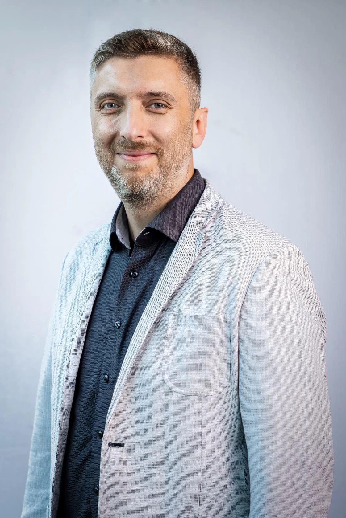 Porträt des Mitarbeiters Mustafa Cura in Businesskleidung vor neutralem Hintergrund – Mitarbeiterfoto für das Unternehmen Heinrich Georg, geeignet für Website oder Unternehmenskommunikation.